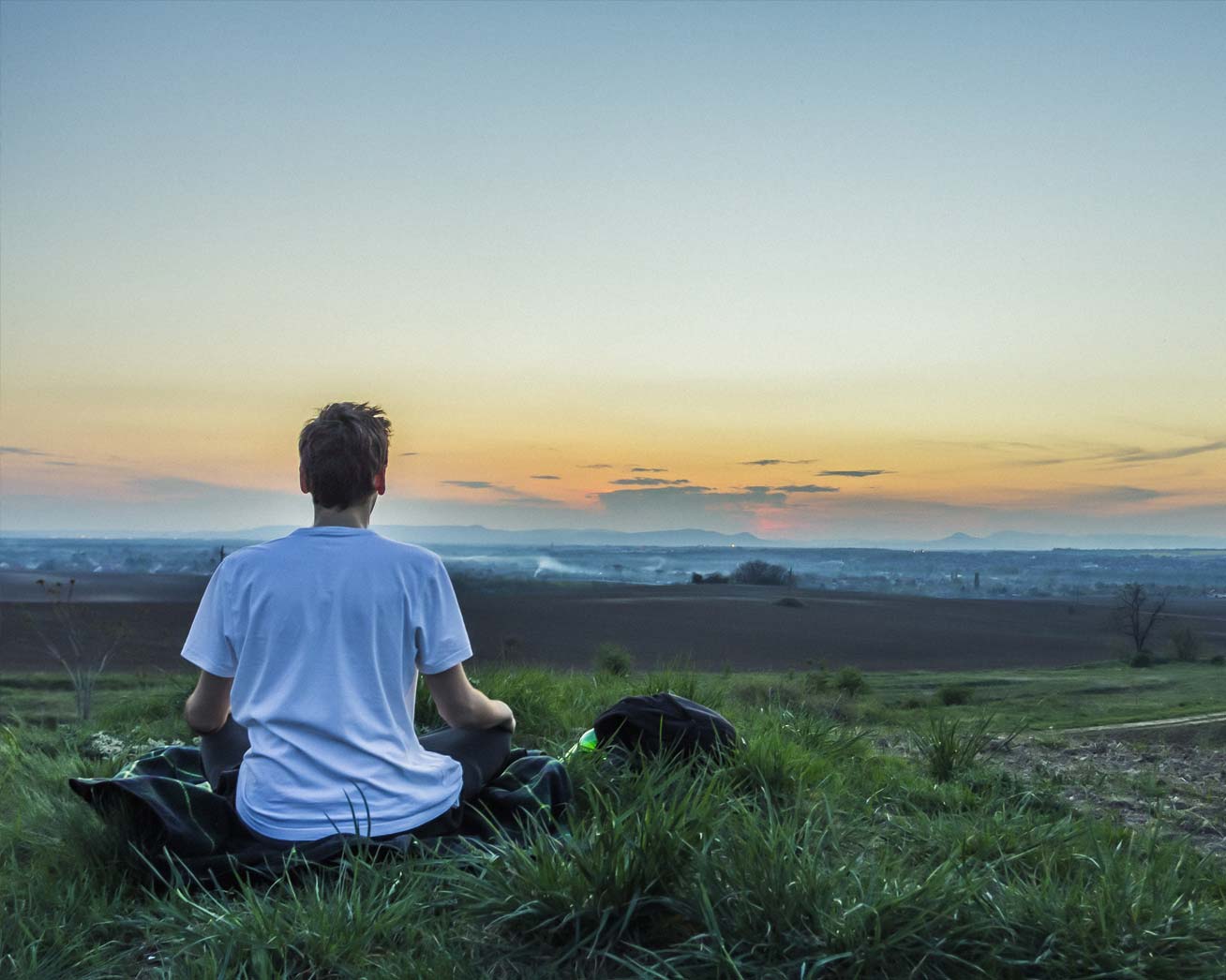 A man meditating and doing qigong on a hill at sunrise